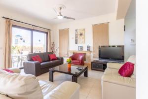 a living room with couches and a flat screen tv at Villa Dora in Argaka