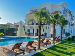 eine Villa mit einem Pool, Stühlen und einem Sonnenschirm in der Unterkunft Apartments Lj in Ulcinj
