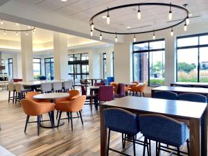 a dining room with tables and chairs and windows at Hilton Garden Inn Oconomowoc in Oconomowoc