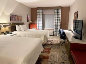 a hotel room with two beds and a flat screen tv at Hilton Garden Inn Oconomowoc in Oconomowoc