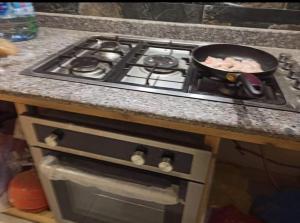 piec z płytą kuchenną i patelnią w obiekcie appartement propre w mieście El Bayadh