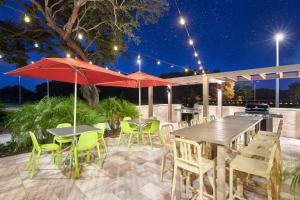 - une terrasse avec des tables, des chaises et des parasols la nuit dans l'établissement Home2 Suites By Hilton Palm Bay I 95, à Melbourne