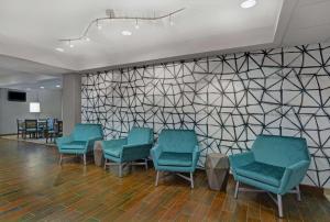 a waiting room with green chairs and a wall with triangles at Hampton Inn Charlotte Monroe in Monroe