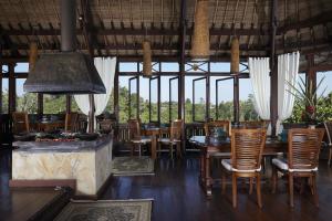 a restaurant with wooden tables and chairs and windows at Bagus Jati Health & Wellbeing Retreat in Tegalalang