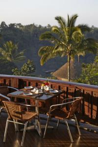 a table and chairs on a deck with a palm tree at Bagus Jati Health & Wellbeing Retreat in Tegalalang