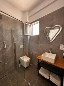uma casa de banho com um chuveiro, um WC e um lavatório. em Hotel Belle Vue em Ksamil