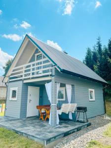 a blue house with a porch and two chairs on a deck at Domek Basiagówka in Lipie