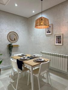 a dining room table with white chairs and a chandelier at Ifrane apartment with swimming pool in Ifrane
