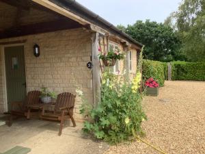 a shed with two chairs and a table and flowers at The Retreat, Clematis cottages, Stamford in Stamford