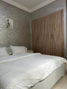a bedroom with a large bed and a wooden cabinet at Ifrane apartment with swimming pool in Ifrane