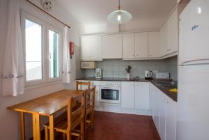cocina con armarios blancos y mesa de madera en Villa Gelabert Ametller, en Cala'n Bosch