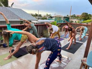 - un groupe de personnes faisant du yoga sur une terrasse dans l'établissement Guest House - V-land, à Haleiwa