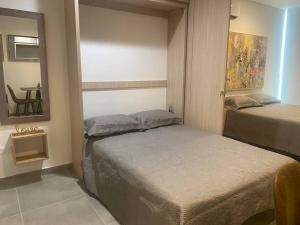 1 dormitorio con 2 camas, espejo y mesa en Hermoso ApartaSuite en Playa Salguero!/Rodadero, en Gaira