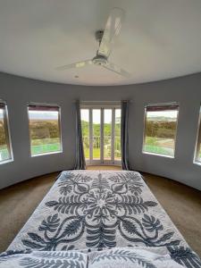 a bedroom with a bed with a ceiling fan and windows at Iro Luxury Retreat in Rarotonga