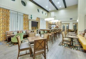 una sala de estar con mesas y sillas y un bar en Hampton Inn & Suites Mooresville, en Mooresville