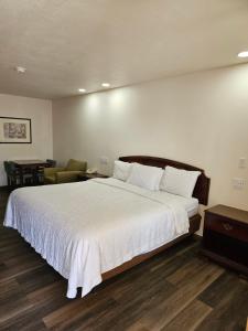 - une chambre avec un grand lit blanc et une chaise dans l'établissement Rodeway Inn, à Tucumcari