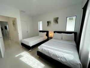 1 dormitorio con 2 camas con sábanas blancas en ! Espectacular casa del bosque !, en Florida City