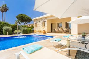 a villa with a swimming pool with chairs and an umbrella at Villa Elite in Droushia