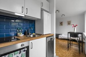 a kitchen with white cabinets and a blue tile wall at Żuromińska Comfort Studio in Warsaw