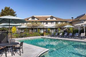 a swimming pool with chairs and a table and an umbrella at Seacliff Inn Aptos, Tapestry Collection by Hilton in Aptos