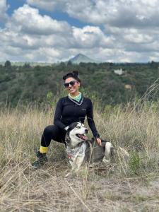 una donna e il suo cane seduti in un campo di Vive en un rancho a Puebla