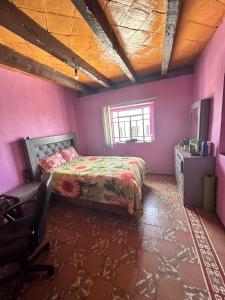 um quarto com paredes cor-de-rosa, uma cama e uma cadeira. em Vive en un rancho em Puebla