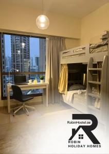Robin Beach Hostel JBR في دبي: غرفة نوم مع سرير بطابقين ومكتب ونافذة