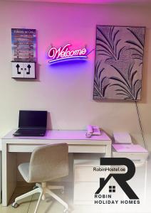 un bureau avec un bureau, un ordinateur portable et un néon dans l'établissement Robin Beach Hostel JBR, à Dubaï