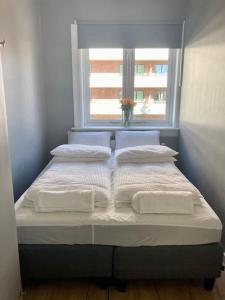 a bed with three pillows and a window in a room at Majorstua, charming and modern 2 bedroom apartment in Oslo