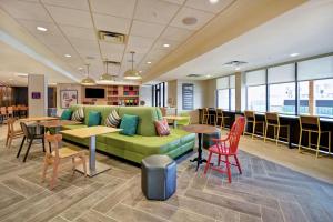 - un hall avec un canapé vert, des tables et des chaises dans l'établissement Home2 Suites By Hilton Eagan Minneapolis, à Eagan