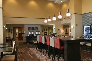 a restaurant with a bar with red and white chairs at Hampton Inn & Suites Lino Lakes in Lino Lakes