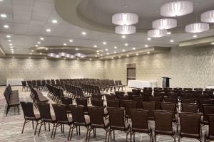 Cette grande chambre comprend des chaises, des tables et des lustres. dans l'établissement DoubleTree by Hilton St. Paul, MN, à Saint Paul
