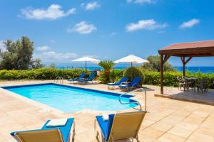 a swimming pool with chairs and a table at Villa Erato in Nea Dimmata