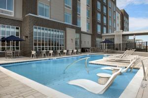 a pool at a hotel with chairs and tables at Hilton Garden Inn Florence Cincinnati Airport South in Florence