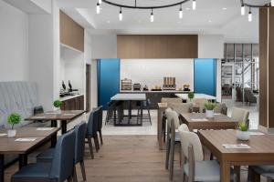 a restaurant with wooden tables and chairs and a kitchen at Hilton Garden Inn Florence Cincinnati Airport South in Florence
