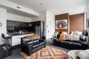 a living room with a black leather couch and a kitchen at Boujee on Bond in Dunedin
