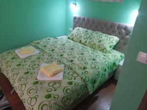 - un lit vert avec 2 serviettes et des oreillers dans l'établissement Apartman ,,LOVAC" Nova Varoš, à Branoševac