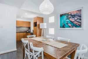 a dining room with a wooden table and white chairs at Midd's on the Beach - luxury beach front apartment in Albany