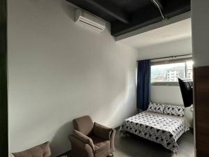 een slaapkamer met een bed, een stoel en een raam bij Asombroso Apto 302 Para Grupos en El Poblado in Medellín