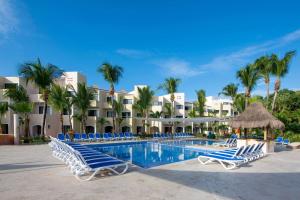 a resort swimming pool with lounge chairs and palm trees at Viva Maya by Wyndham, A Trademark All Inclusive Resort in Playa del Carmen