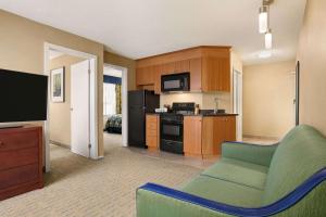a living room with a couch and a kitchen at Travelodge by Wyndham Oshawa Whitby in Oshawa