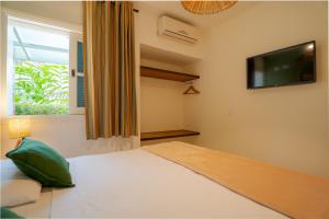 1 dormitorio con 1 cama, TV y ventana en Pousada Una en Barra do Una