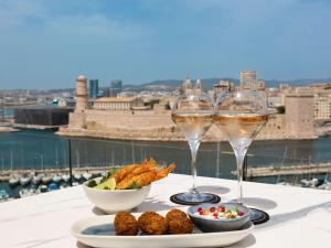 dos copas de vino y un plato de comida en una mesa en Sofitel Marseille Vieux-Port, en Marsella