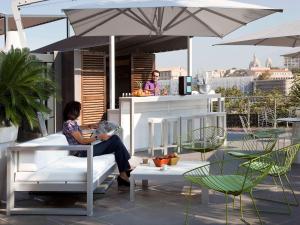 une femme assise sur une chaise sous un parapluie dans l'établissement Novotel Marseille Vieux Port, à Marseille