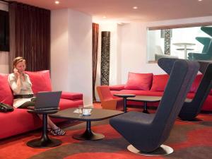 a woman sitting on a couch with a laptop in a room at Novotel Marseille Vieux Port in Marseille