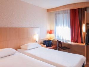 una camera d'albergo con due letti, una scrivania e una finestra di ibis Moulins a Moulins
