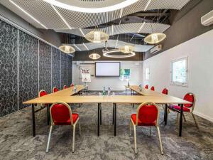 a conference room with a table and chairs and a screen at Mercure Antibes Sophia Antipolis in Valbonne