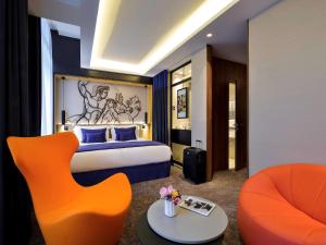 a hotel room with a bed and a orange chair at Grand Hotel La Cloche Dijon - MGallery in Dijon