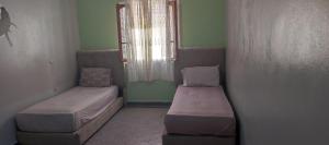 a small room with two beds and a window at amine adnane in Safi