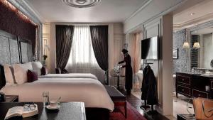a woman standing in a bedroom with a large bed at Sofitel Legend Metropole Hanoi in Hanoi